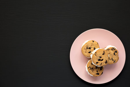 Homemade Chocolate Chip Cookie Ice Cream Sandwich on a pink plate on a black background, top view....