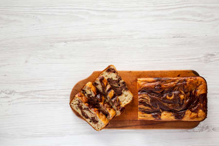 Homemade Chocolate Banana Bread on a rustic wooden board on a white wooden background, top view....