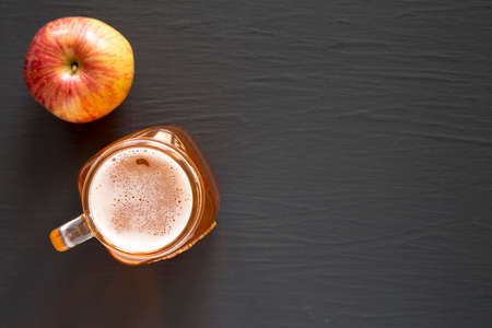 Hard Apple Cider Ale in a Glass Jar Mug on a black surface, top view. Flat lay, overhead, from...