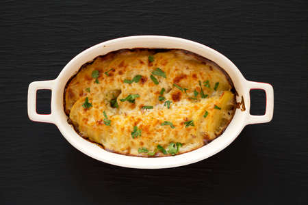 Homemade Scalloped Potatoes on a black surface, top view. Flat lay, overhead, from above.