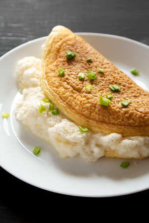 Homemade Fluffy Omelet on a white plate on a black background, low angle view. Close-up.の写真素材