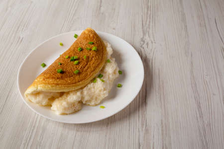 Homemade Fluffy Omelet on a white plate on a white wooden background, side view. Copy space.の写真素材