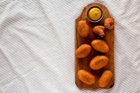 Homemade Mini Corn Dogs on a rustic wooden board, top view. Flat lay, overhead, from above. Copy...