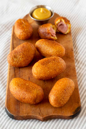 Homemade Mini Corn Dogs on a rustic wooden board, side view.の写真素材