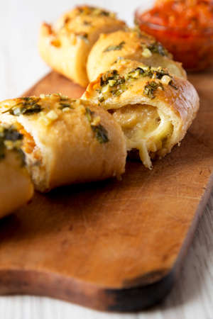 Homemade Chicken Parmesan-Stuffed Garlic Bread on a rustic wooden board on a white wooden background, side view. Close-up.の写真素材