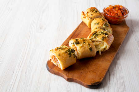Homemade Chicken Parmesan-Stuffed Garlic Bread on a rustic wooden board on a white wooden table, side view. Copy space.の写真素材