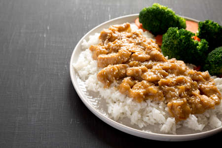 Homemade Orange Chicken with White Rice, Broccoli and Carrot on a plate on a black background, side view. Copy space.の写真素材