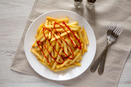 Homemade French Fries with Ketchup, Salt and Pepper on a white plate on a white wooden table, top view. Flat lay, overhead, from above.の写真素材