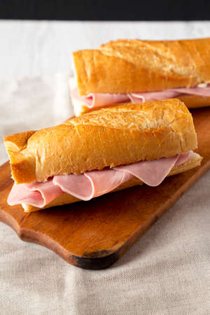 Homemade Parisian Jambon-Beurre Sandwich on a rustic wooden board, side view.の写真素材