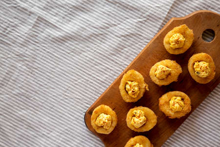 Homemade Deep-fried Deviled Eggs with Paprika on a rustic wooden board, top view. Flat lay,...