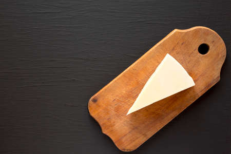 Pecorino Romano Cheese on a rustic wooden board on a black background, top view. Flat lay, overhead, from above. Copy space.の写真素材