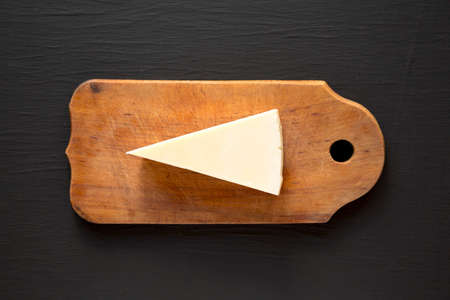 Pecorino Romano Cheese on a rustic wooden board on a black surface, top view. Flat lay, overhead, from above.の写真素材