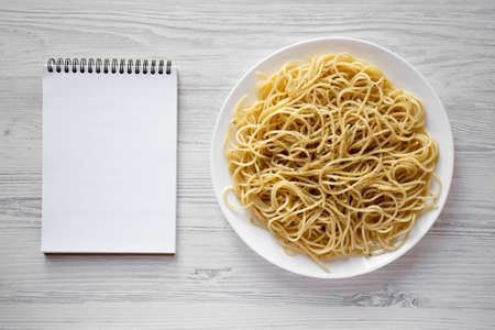 Homemade Cacio E Pepe Pasta with Pecorino Romano and Pepper on a white plate, blank notepad, top view. Overhead, from above.の写真素材