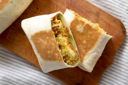 Homemade Breakfast Egg Burrito with Avocado and Bacon on a rustic wooden board, top view. Flat lay, overhead, from above. Close-up.の写真素材