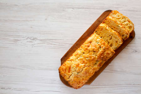Homemade Cheesy Bread Loaf on a rustic wooden board on a white wooden surface, top view. Copy space.の写真素材