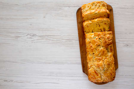 Homemade Cheesy Bread Loaf on a rustic wooden board on a white wooden background, top view. Flat...