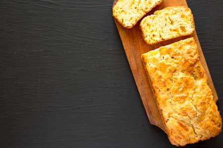 Homemade Cheesy Bread Loaf on a rustic wooden board on a black background, top view. Flat lay, overhead, from above. Copy space.の写真素材