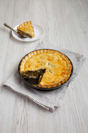 Homemade Chicken Pot Pie on a white plate on a white wooden background, side view.