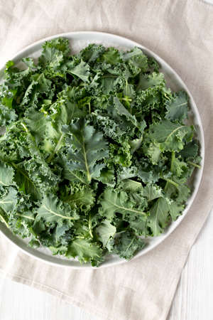 Raw Organic Baby Kale on a gray plate on a white wooden surface, top view. Flat lay, overhead, from above.の写真素材