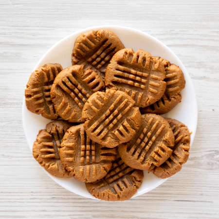 Homemade Peanut Butter Cookies on a plate on a white wooden surface, top view. Flat lay, overhead,...