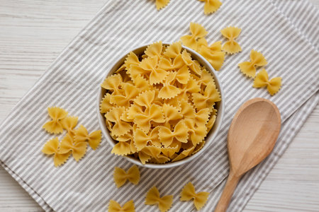 Dry Organic Farfalle Pasta in a Bowl on a white wooden background, top view. Flat lay, overhead, from above.の写真素材