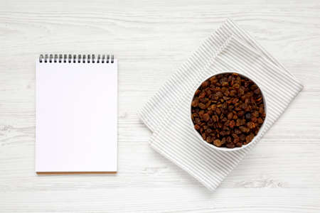 Dried Brown Raisins in a Gray Bowl, blank notepad, top view. Flat lay, overhead, from above.の写真素材
