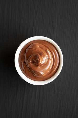 Homemade Chocolate Hazelnut Spread in a Bowl on a black background, top view. Flat lay, overhead,...