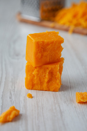 Organic Sharp Cheddar Cheese on a white wooden background, side view.