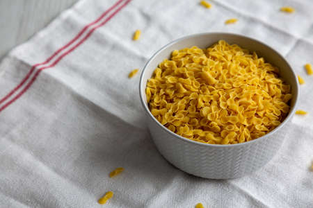 Healthy Dry Farfalline Pasta in a Bowl, side view. Space for text.