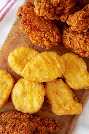 Tasty Fastfood: Chicken Nuggets, Wings and Tenders on a rustic wooden board, top view. Overhead,...