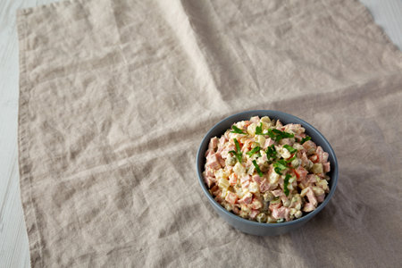 Homemade Olivier salad in a Bowl on a white wooden background, low angle view. Space for text.の写真素材