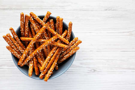 Baked Pretzel Sesame Sticks in a Bowl on a white wooden background, top view. Flat lay, overhead, from above. copyspace.の写真素材