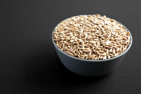 Raw Organic Sunflower Seed Kernels in a Blue Bowl, side view. copyspace.
