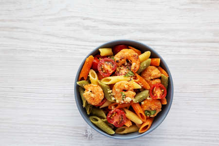 Homemade Tri-Color Penne Salad with Shrimp, Tomato and Basil Bread Crumbs in a Bowl, top view. Flat...