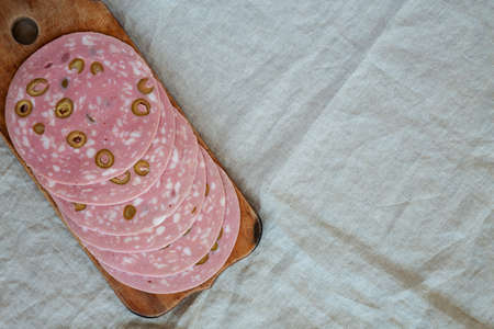 Organic Sliced Mortadella Sausage with Olives on a rustic wooden board, top view. Flat lay, overhead, from above. copyspace.の写真素材