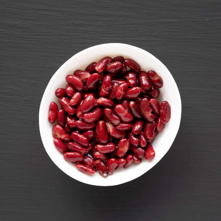 Red Organic Kidney Beans in a White Bowl on a black background, top view. Flat lay, overhead, from...