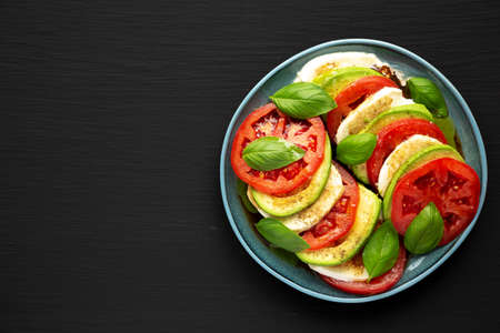 Homemade Organic Avocado Caprese Salad on a Plate on a black background, top view. Flat lay, overhead, from above. copyspace.の写真素材