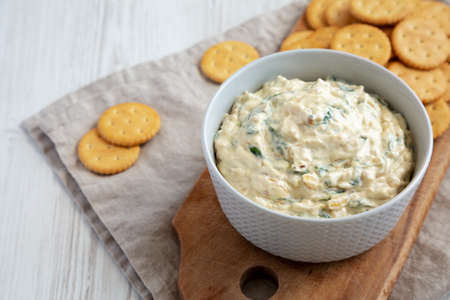 Homemade Caramelized Onion and Spinach Dip with Salty Round Crackers, side view.