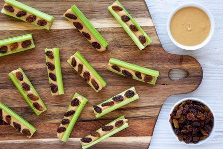 Homemade ants on a log with celery, peanut butter and raisins on a wooden board, top view.の写真素材