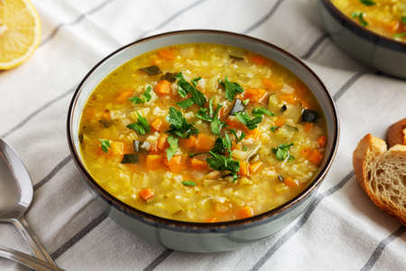 Homemade fresh lemon rice soup in a bowl, side view.の写真素材