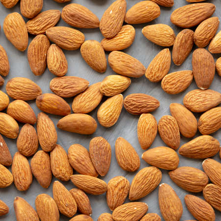 Raw brown almonds on a gray surface, top view. Flat lay, overhead, from above.の写真素材