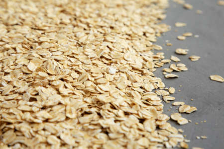 Dry Organic Rolled Oats on a gray background, side view.