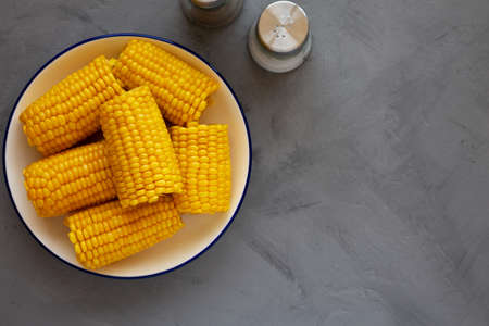 Homemade Steamed Corn on the Cob with Butter on a Plate, top view. Flat lay, overhead, from above....