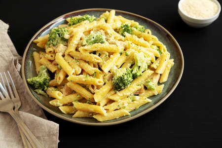 Homemade Penne Alfredo Pasta with Chicken and Broccoli on a Plate on a black background, side view.の写真素材