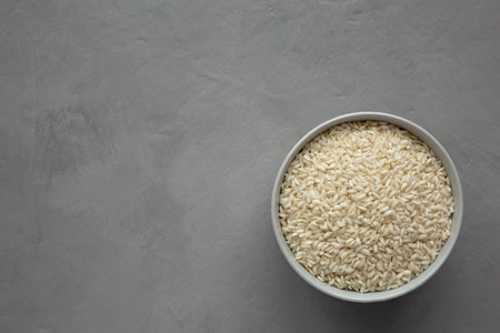 Raw Organic Carnaroli Rice in a Bowl on a gray background, top view. Overhead, from above, flat lay. copyspace.の写真素材
