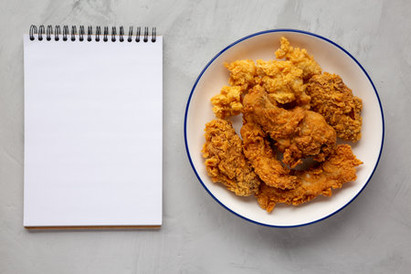 Chicken Popcorn, Wings and Tenders with BBQ Sauce on a plate, blank notepad on a gray background, top view. Flat lay, overhead, from above.の写真素材