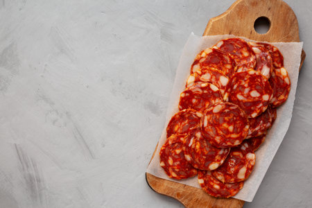 Spanish chorizo salami sausage on a rustic wooden board on a gray background, top view. Flat lay, overhead, from above.の写真素材