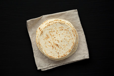 Stack of Whole Wheat Flour Tortillas on a black background, top view. Flat lay, overhead, from above.の写真素材