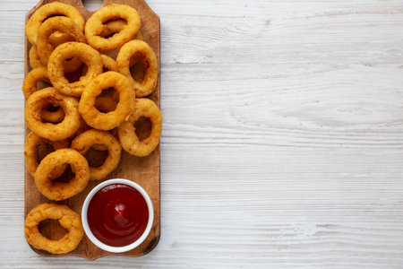 Homemade Crispy Deep-Fried Onion Rings with Ketchup on a rustic wooden board, top view. flat lay. Space for text.の写真素材