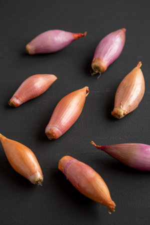 Raw Organic Shallots on a Black surface, side view.